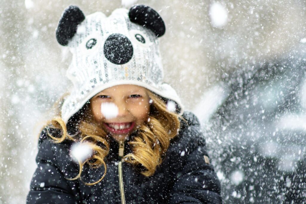 Happy little girl having fun in snowy winter day