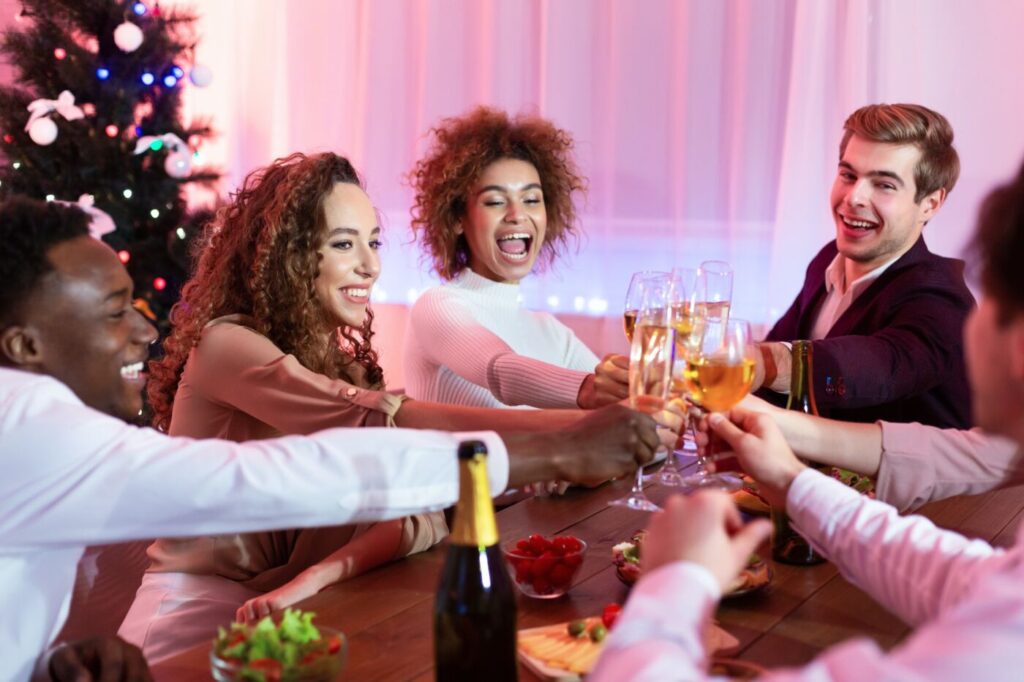 Joyful Friends Celebrating New Year Sitting At Table Indoors
